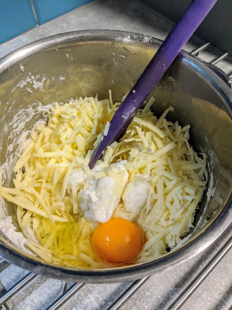 Add grated cheese and egg to the cooled mixture.