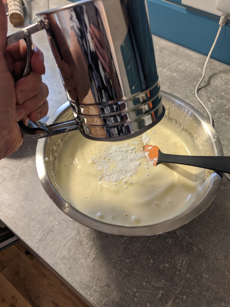 Shifting the flour mixture in the egg and sugar foam gently folding with a spatula.