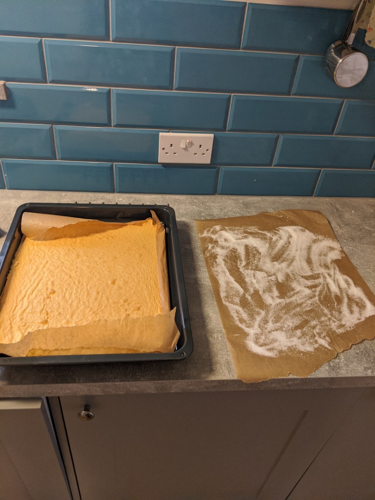 Coat another piece of baking paper with caster sugar, and turn the baked cakesheet on it.