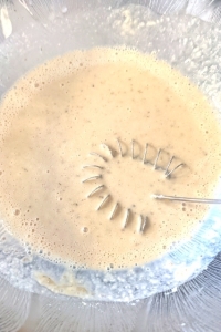 Mixture of gluten-free flour mix, yoghurt, milk, seasoning and yeast in a  glass 
bowl with a spiral whisk.