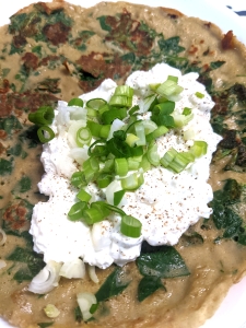Gluten-Free Spinach pancakes with two different style fillings - on the left there is a large spinach pancake with cottage cheese and finely chopped spring onion and black pepper on top. 