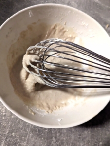 Gluten-Free hot cross bun batter to mae the cross falling of the whisk. The consistency of the mixture is slightly thick, you want the mixture being more like thick slowly moving caramel sauce, so that it is pipeable and doesn't go hard when baking.